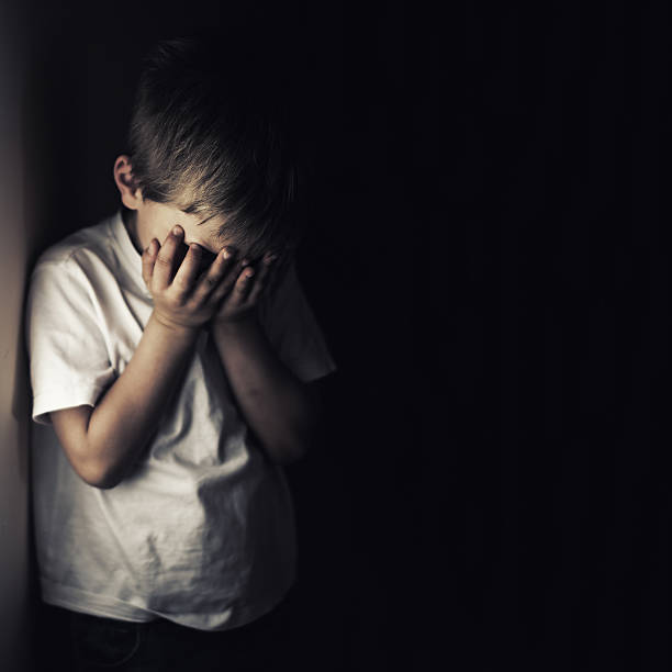 bambino depresso che piange tenendo la testa in mano - physical abuse foto e immagini stock