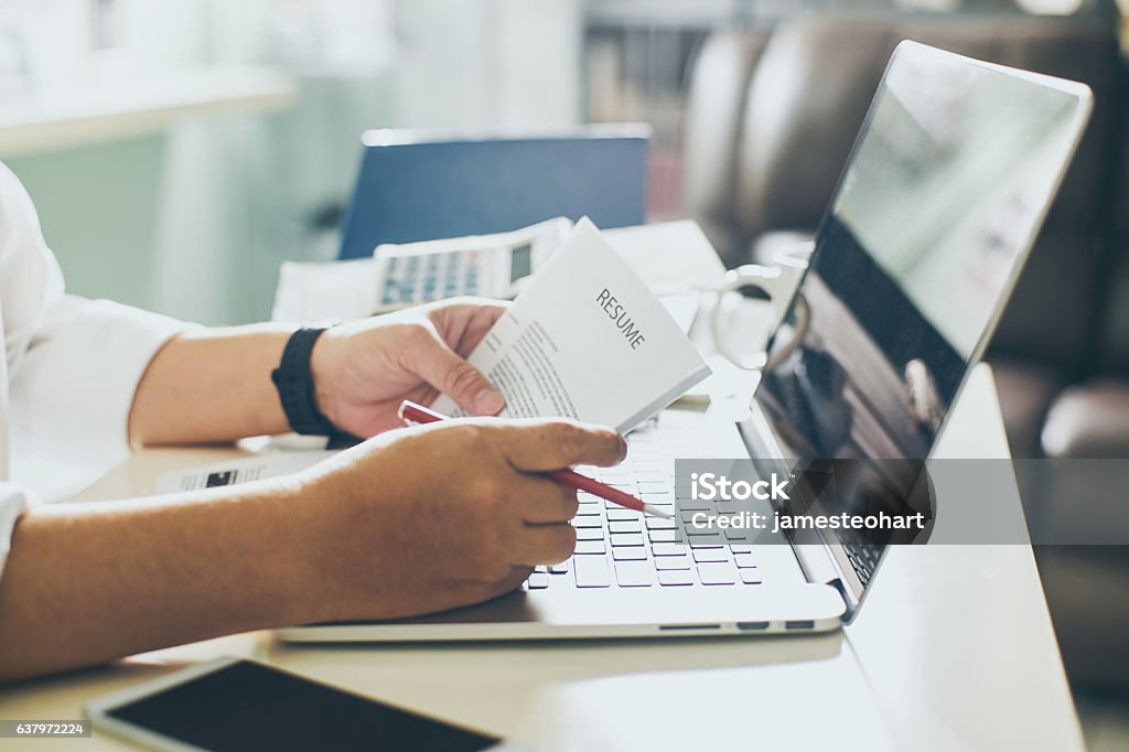 Un homme d’affaires examine son CV sur son bureau - Photo de CV libre de droits