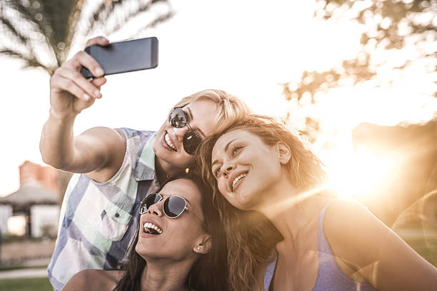 Young happy friends enjoying a day in nature while taking a selfie with smart phone.