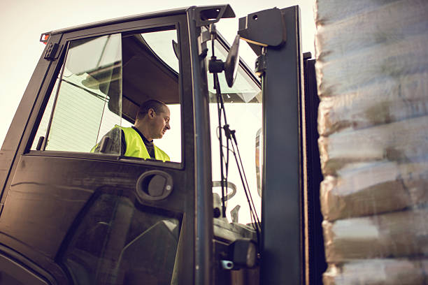 istock Mid adult worker driving a forklift with a pallet. 637973436