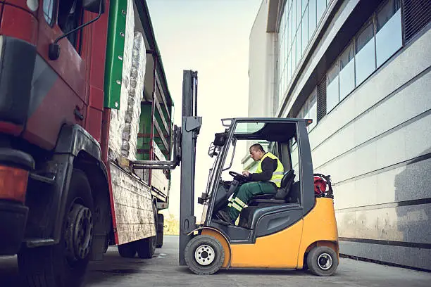 Photo of Worker loading pallet with a forklift into a truck.