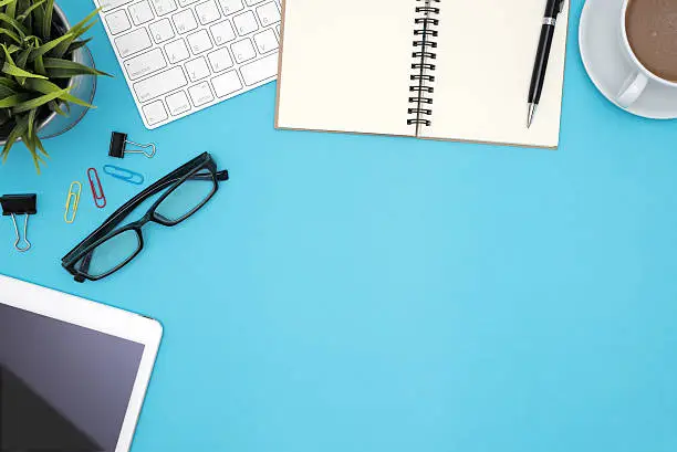 Photo of Office desk table with supplies and computer on blue background