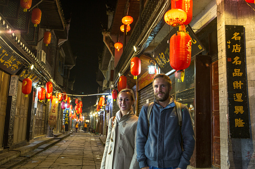 Young traveling couple in an alley of the ancient village of fenghuang, China.