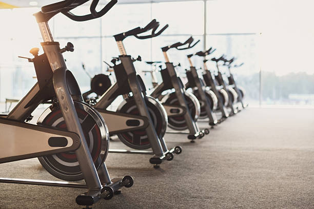 Modern gym interior with equipment, fitness exercise bikes Modern gym interior with equipment. Row of training exercise bikes detail, backlight. Healthy lifestyle concept exercise machine photos stock pictures, royalty-free photos & images