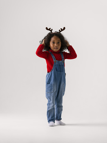 African little girl wearing reindeer horns full length Portrait on plain background