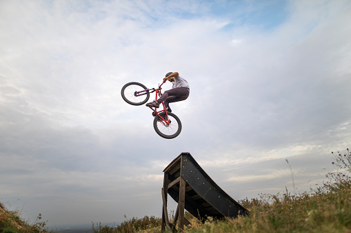 Low angle view of freestyle bmx rider doing straight air jump over sports ramp against the sky.