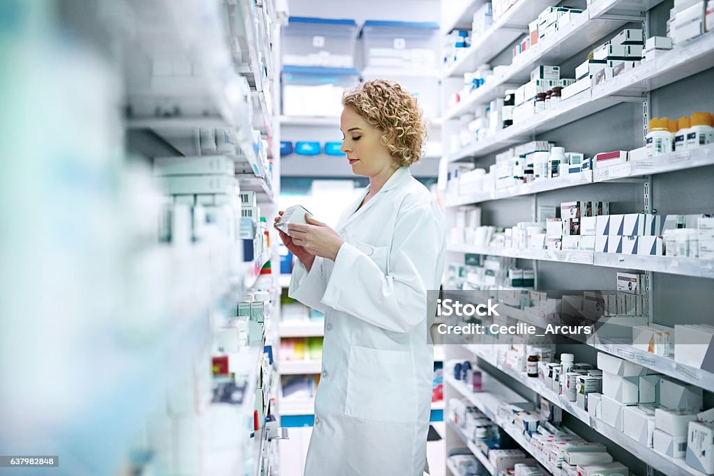 Let the expert find the treatment best suited for you Shot of a pharmacist looking through the shelves at a chemist Pharmacy Stock Photo
