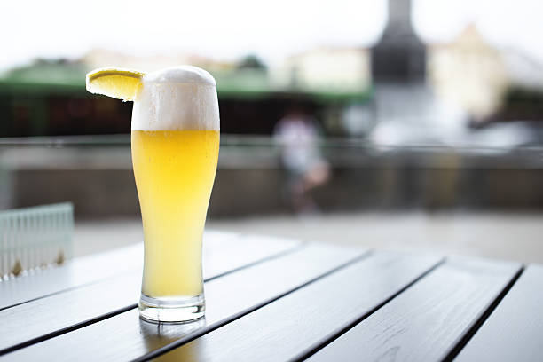 weizenbier mit zitronenscheibe auf dem tisch - weizenbier stock-fotos und bilder