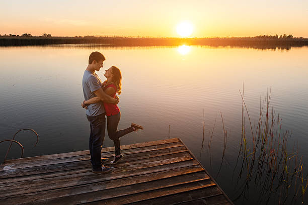 istock Young romantic couple at sunset enjoying on a pier. 637991438