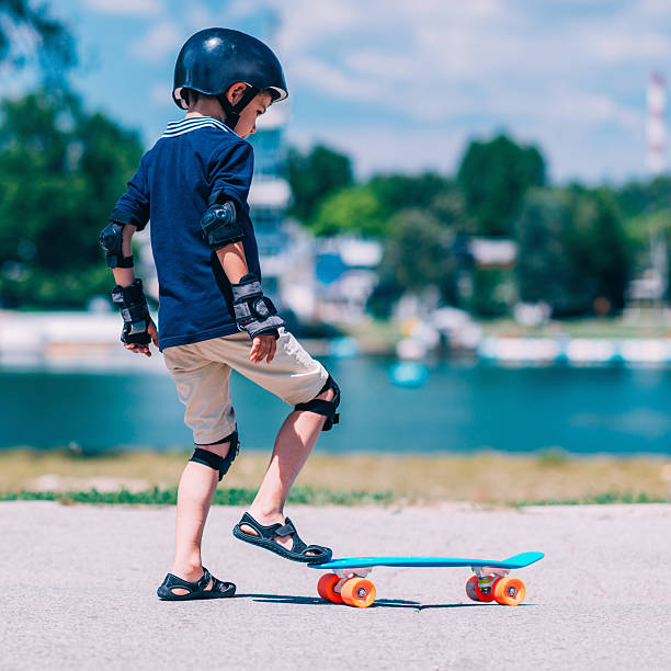 Little boy with skateboard Little boy with skateboard by the lake elbow pad stock pictures, royalty-free photos & images