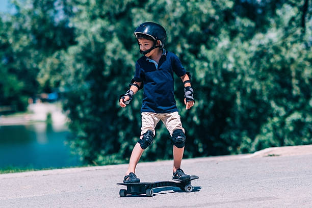 Little boy on the snakeboard Little boy on the snakeboard by the lake elbow pad stock pictures, royalty-free photos & images