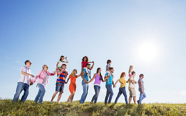 istock Group of people holding hands and walking walking against sky. 637995384
