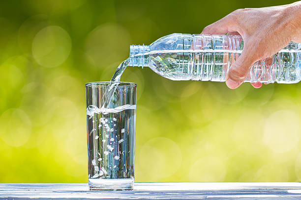 istock Man's hand pouring water into glass on blurred bokeh background 637998018