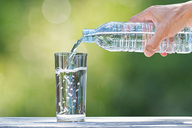 istock Man's hand pouring water into glass on blurred bokeh background 637998502