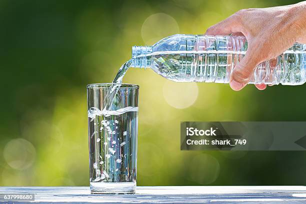 Die Hand Des Mannes Gießt Wasser In Glas Auf Verschwommenen Bokehhintergrund Stockfoto und mehr Bilder von Trinken