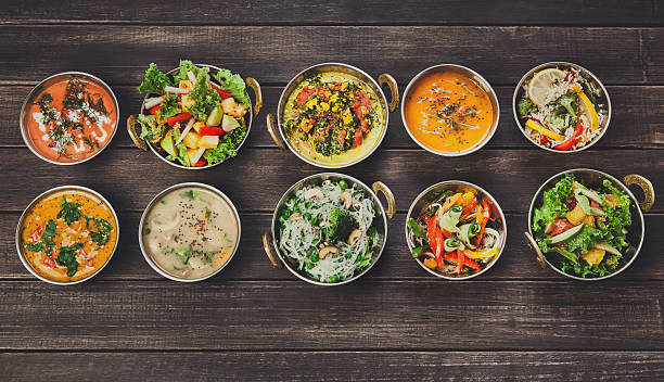 Vegan and vegetarian indian cuisine hot spicy dishes Vegan or vegetarian restaurant dishes top view, hot spicy indian soups, rice and salads in copper bowls. Traditional indian cuisine meal assortment on wood background. Healthy eastern local food side dish stock pictures, royalty-free photos & images