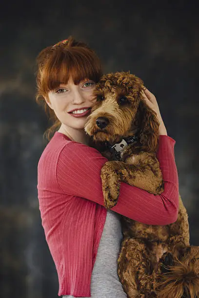 Woman posing with her pet dog in her arms.