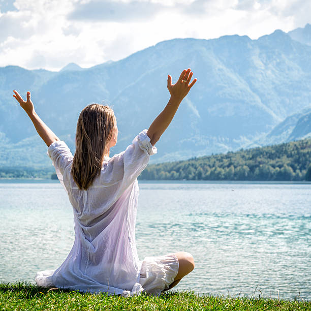 donna meditare sul lago - equanimity foto e immagini stock