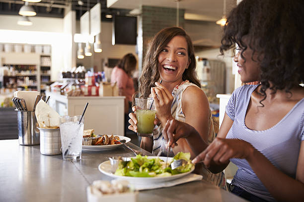 dos mujeres disfrutando de la cita para almorzar en el restaurante delicatessen - comida del mediodía fotografías e imágenes de stock