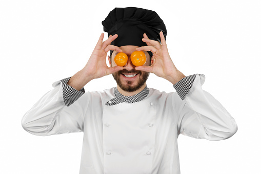 happy chef covering his eyes with tomatoes isolated on white background