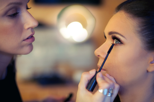 Makeup artist applies mascara. Beautiful woman face. Perfect makeup