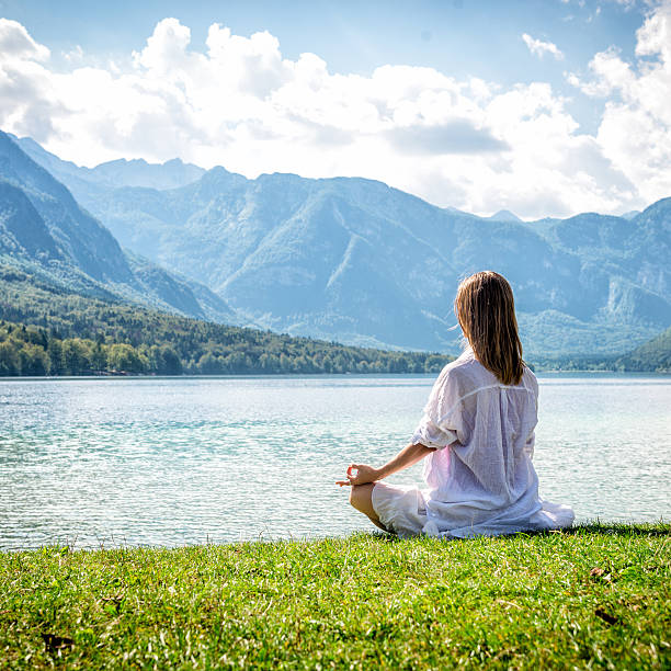 istock Woman meditating at the lake 638007576