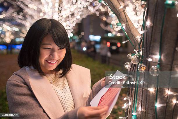 クリスマスライトの下でクリスマスカードを開く若い女性