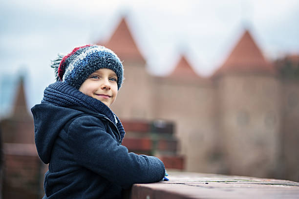 Little tourists visiting medieval city walls in the center of Warsaw. Cold day, overcast sky.