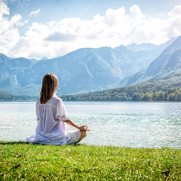 istock Woman meditating at the lake 638013026