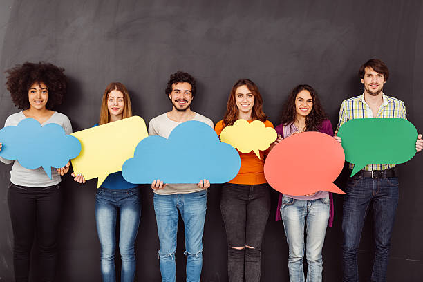 Happy friends holding speech bubbles Group of young people holding speech bubbles against blackboard multi ethnic group college student group of people global communications stock pictures, royalty-free photos & images