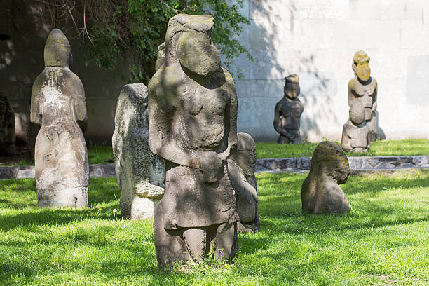Decapitated statue with the head resting on the ground near the feet and a sign reminding people not to lose their heads.