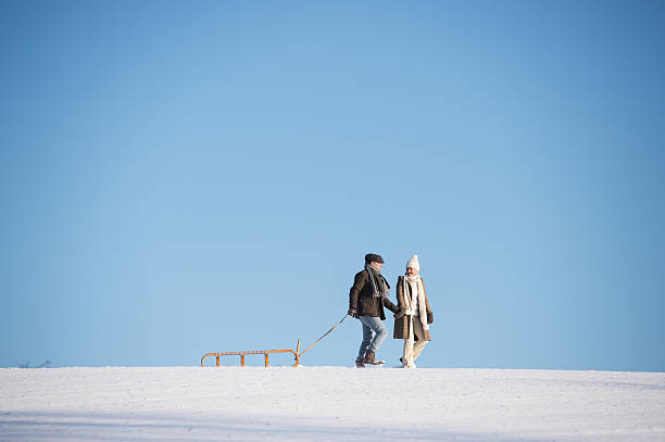 istock Beautiful senior couple on a walk pulling sledge, winter day. 638016396
