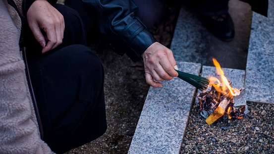 A man is setting fire to incense sticks in Japan.
