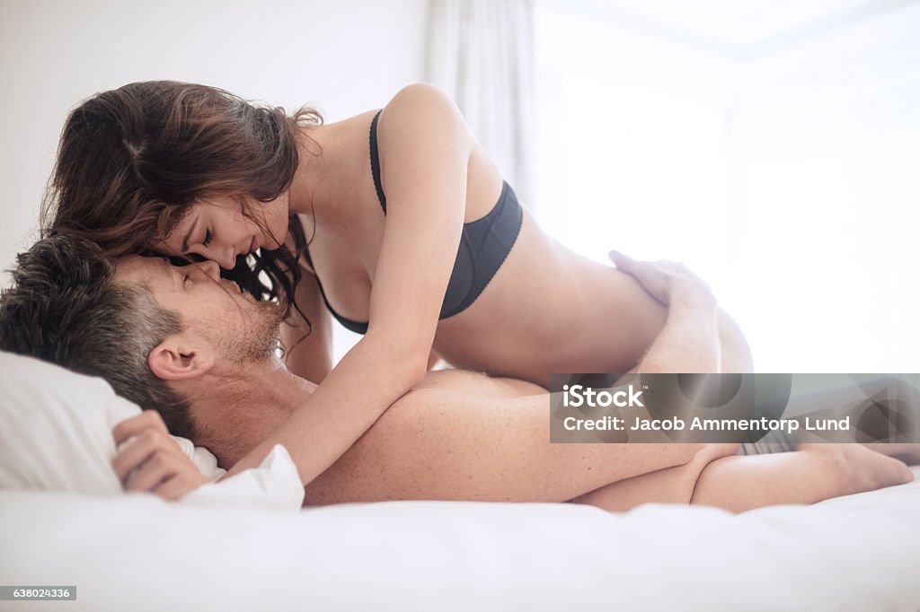 Erotic woman on top of man Erotic woman on top of man lying on bed. Sensual young couple making love in bedroom. Sex and Reproduction Stock Photo