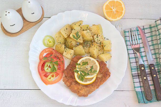 Wiener schnitzel with potatoes in plate on table