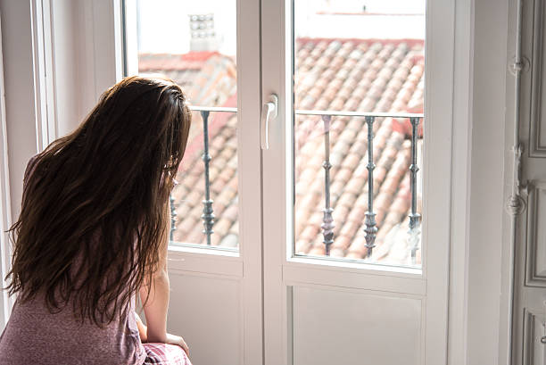istock women sitting by the window thoughtful 638030434
