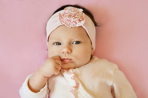 istock Serious baby girl looking at camera lying on pink background 638032952