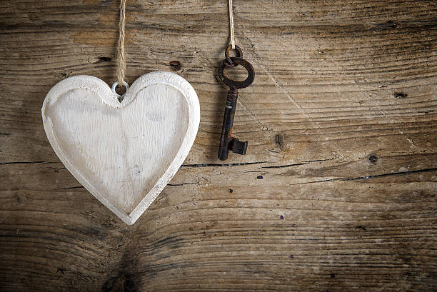 istock Heart and old key hanging on a rustic wooden wall 638036032