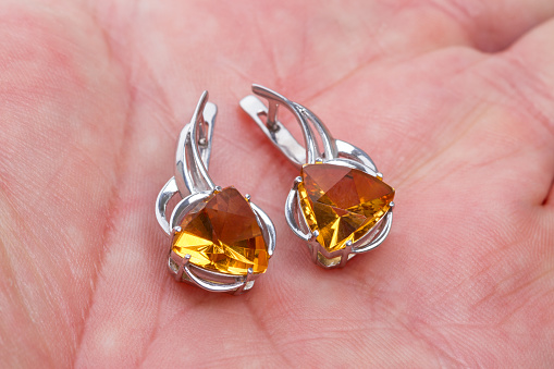 Silver earrings with citrine on palm closeup