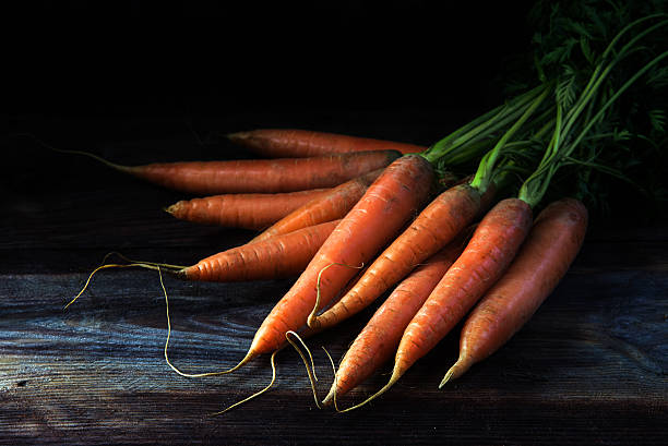 istock Fresh carrots with leaves on dark rustic wood, black background 638038240