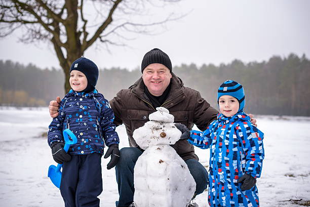istock Two little siblings boys making a snowman with grandfather, playing 638042304