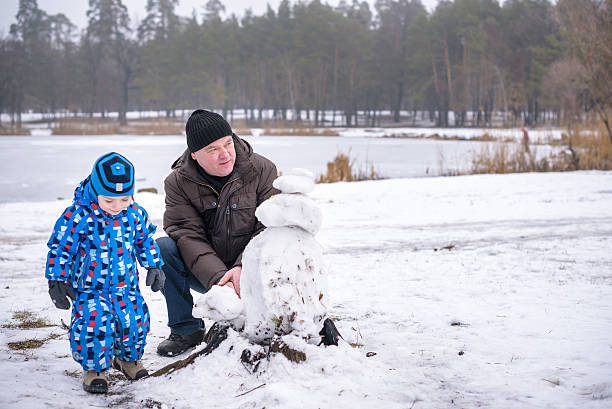 istock Little siblings boy making a snowman with grandfather, playing and 638042614