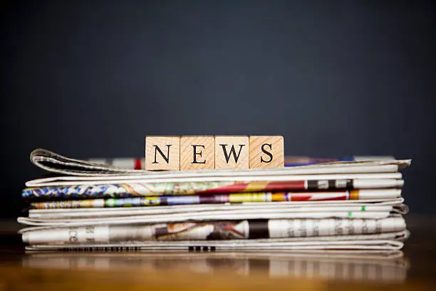 stack of newspapers and article writen with wooden blocks