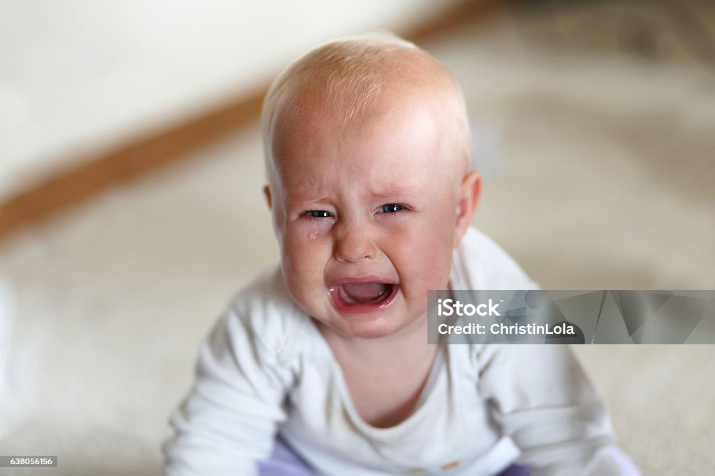 Crying 6 Month Old Baby Girl A cute, but sad 6 month old baby girl is crying as she looks at the camera in her home. Baby - Human Age Stock Photo