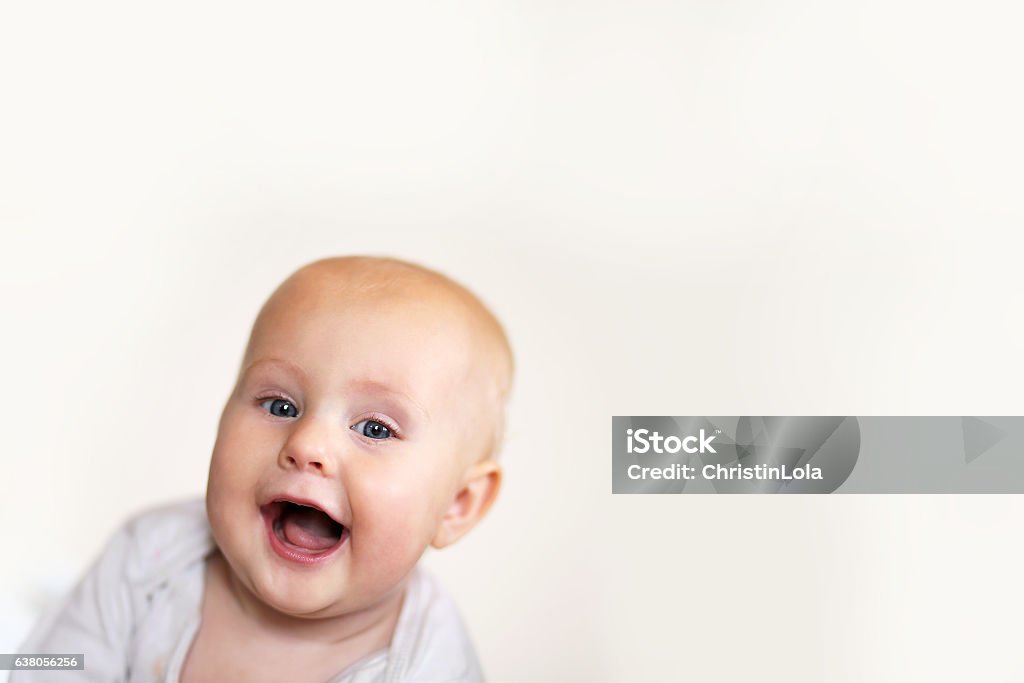 Happy Toothless Baby Girl Smiling A cute, happy 5 month old baby girl is smiling a toothless grin at the camera on a white background. Baby - Human Age Stock Photo