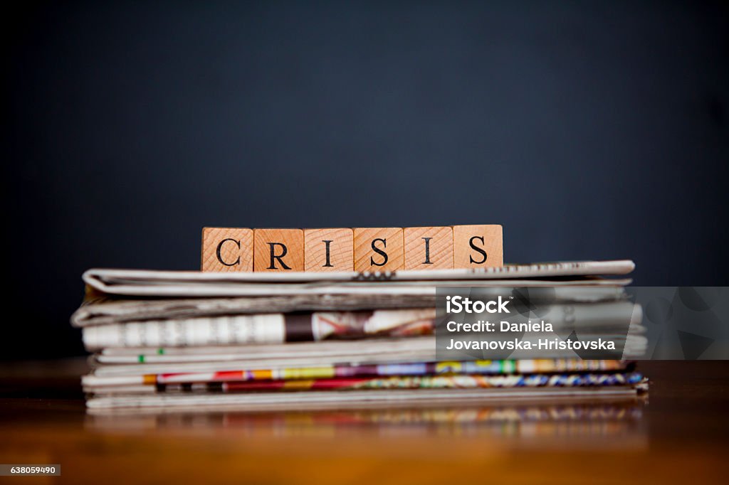 crisis stack of newspapers and article writen with wooden blocks Crisis Stock Photo