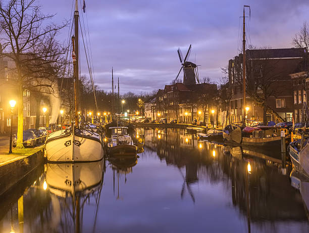 Old Dutch city canal with barges wind mill reflections stock photo