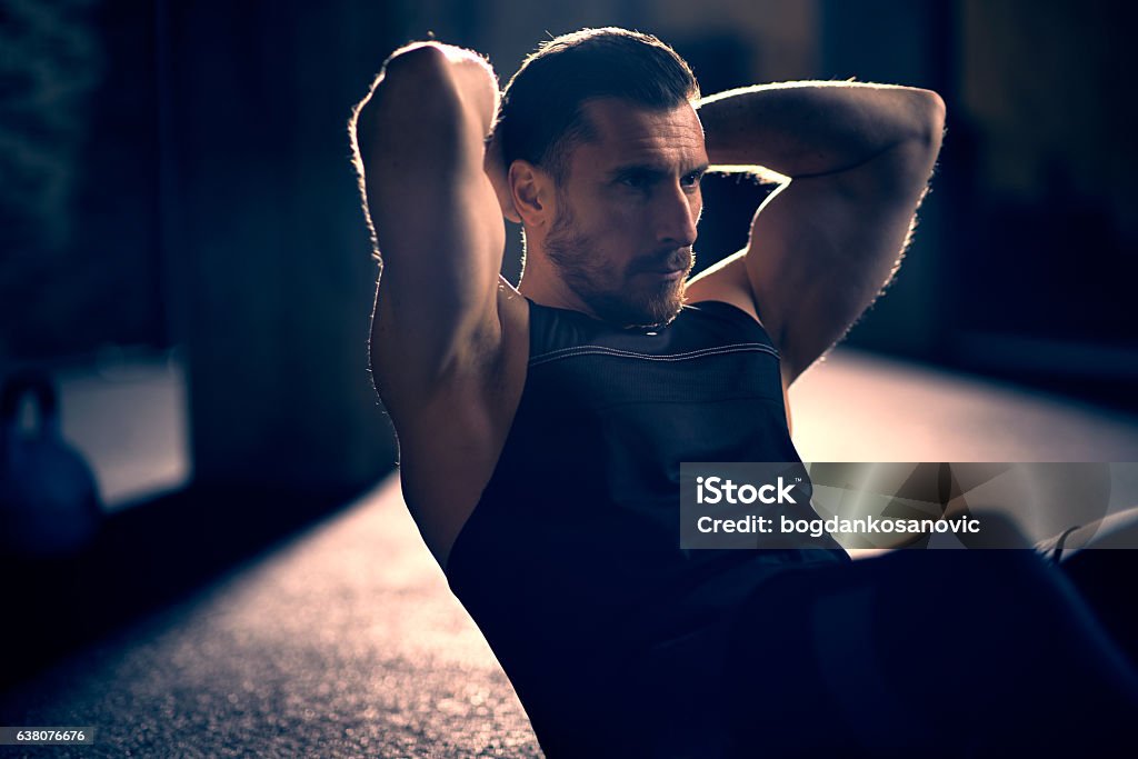 Hombre haciendo sit-ups - Foto de stock de Oscuro libre de derechos