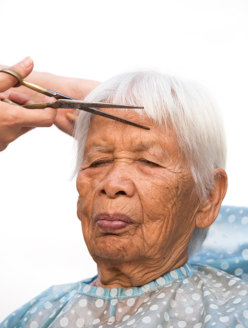 Hair stylist cutting senior woman's gray hair