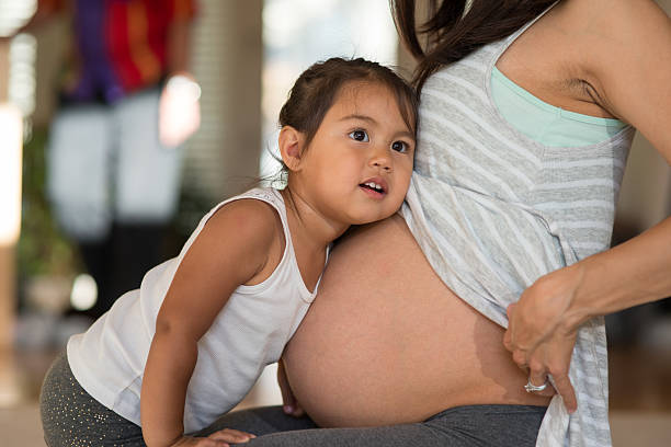 cute toddler listening to her pregnant mother's belly - mother exercising baby dieting imagens e fotografias de stock